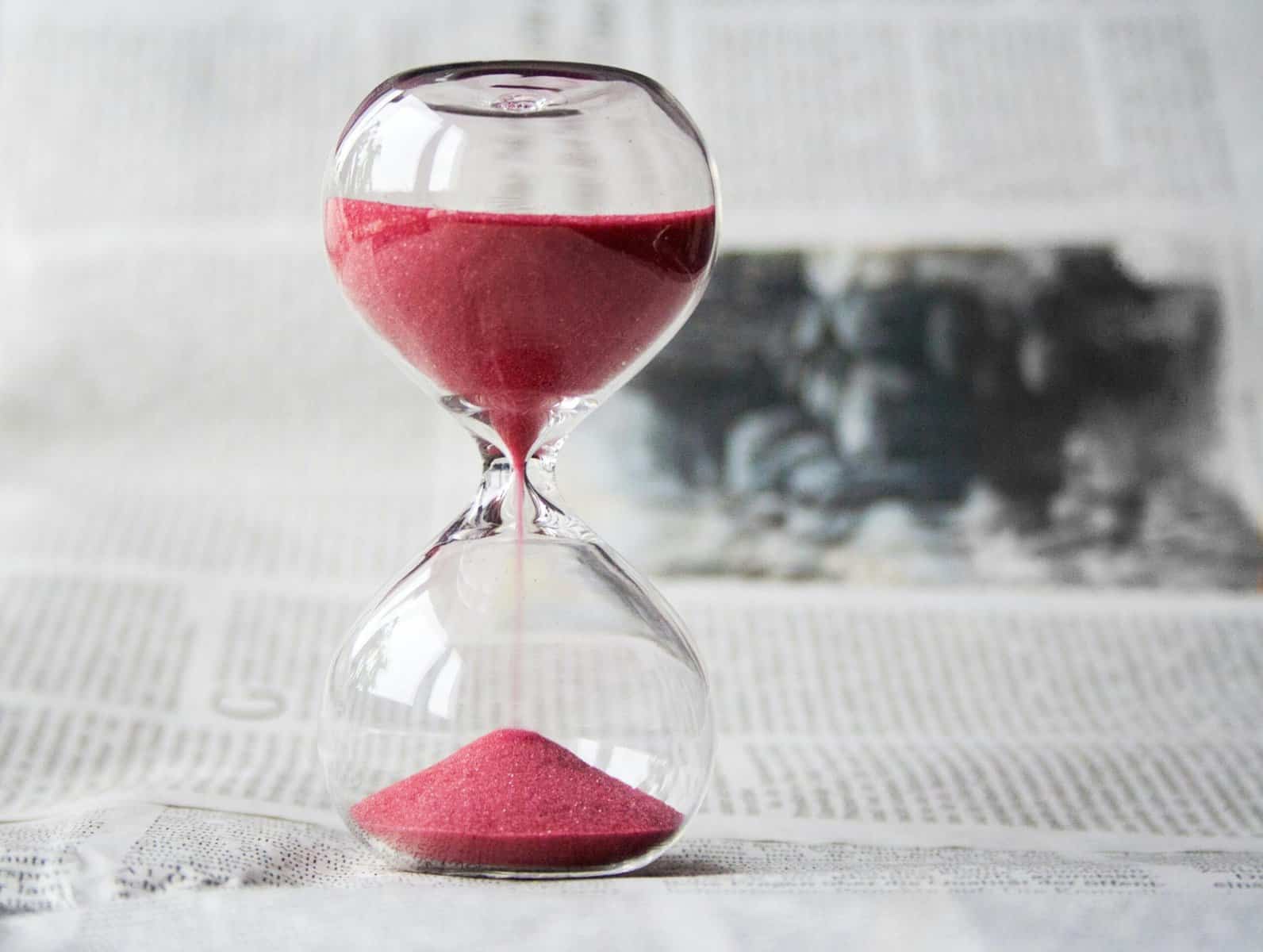 A hourglass timer on a table ontop of a newspaper