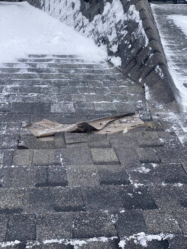 Broken roof shingle in winter on a residential roof