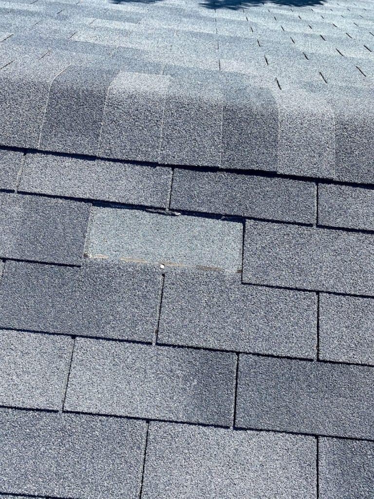 A home in Calgary missing a single shingle from the perspective of a roofer on the roof.