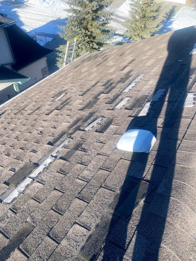 An old roof with many missing shingles, indicating a roof replacement might be better.