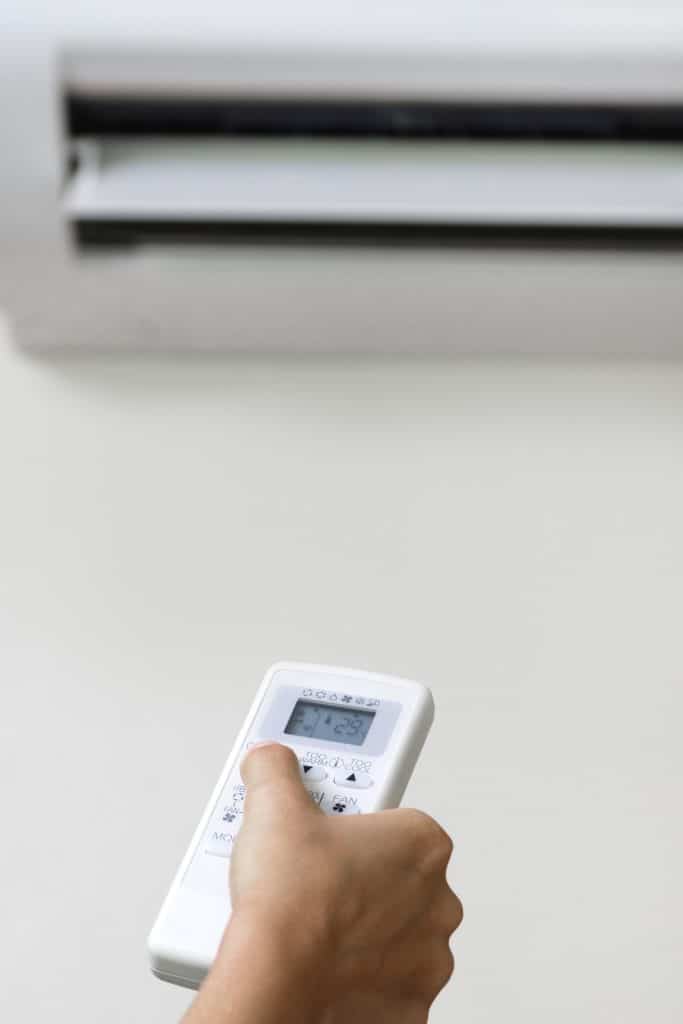 An individual operating an air conditioner in their home, demonstrating the significance of energy efficiency.