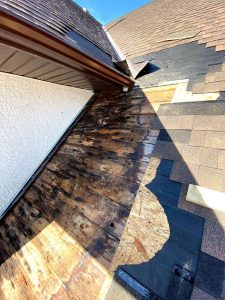 Roof surface damaged by excessive rain, shingles are torn up in a spot where the rain was concentrated due to a roof valley.