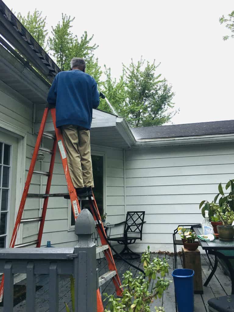 Man cleaning his gutters in the fall on his residential property